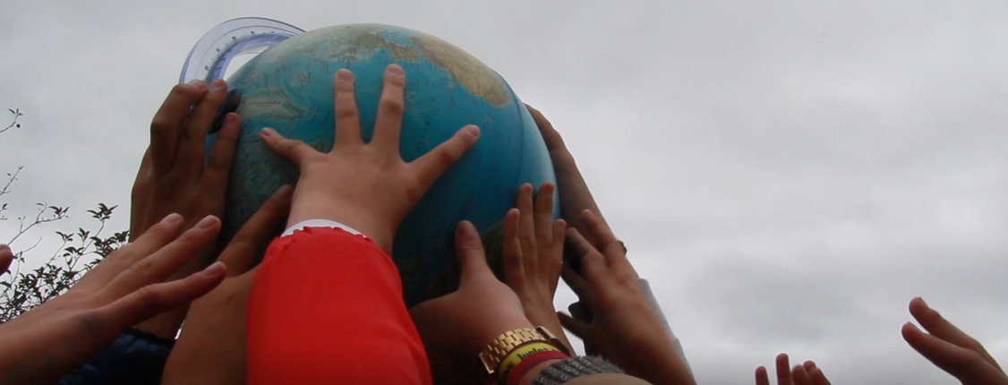 Children's hands raising a globe in the air.